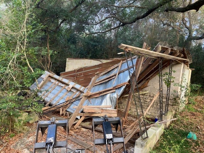 Before site clearing with a collapsed outbuilding and debris pile.