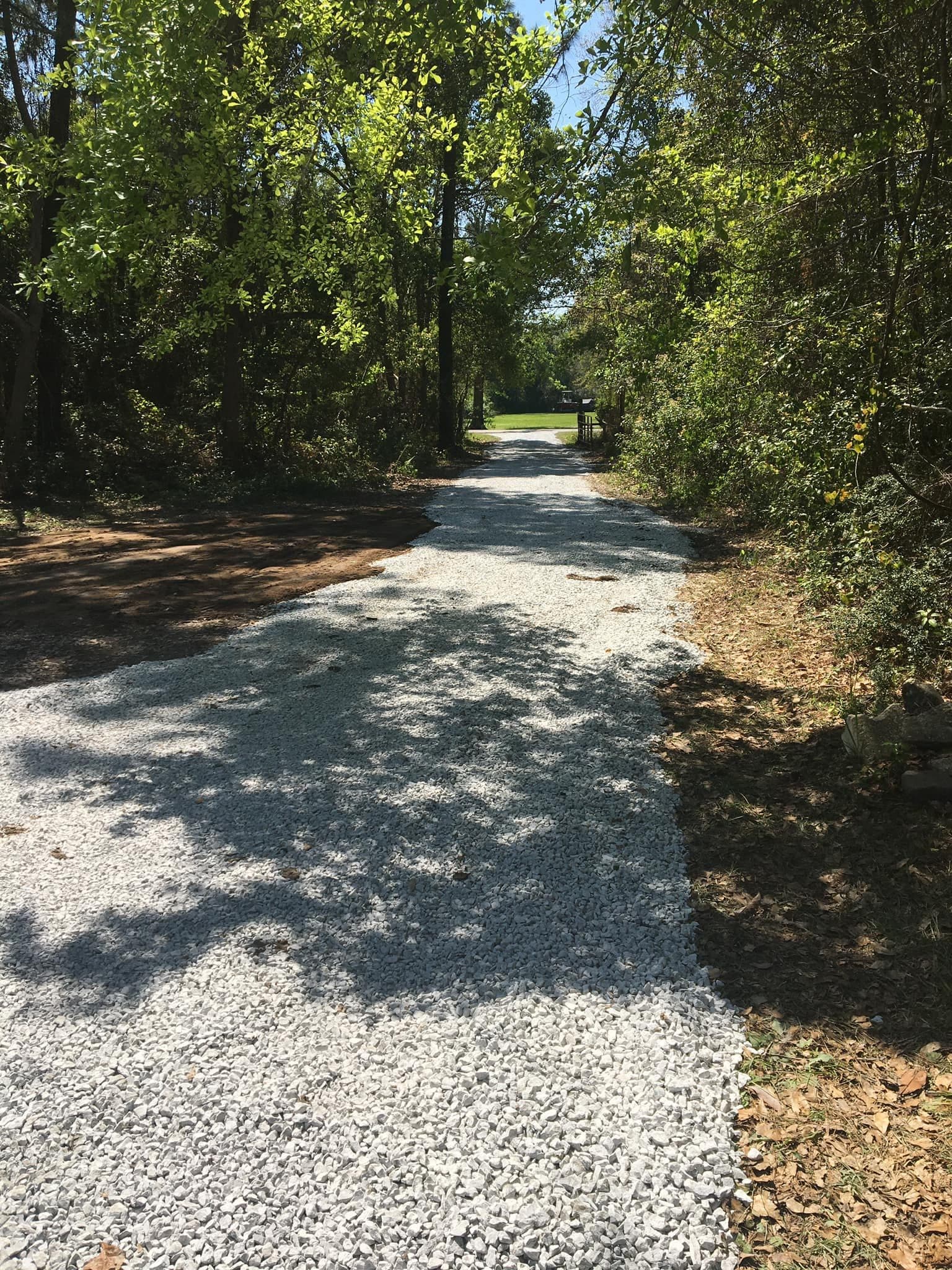 After gravel delivery on a wooded access road with a fresh gravel surface.