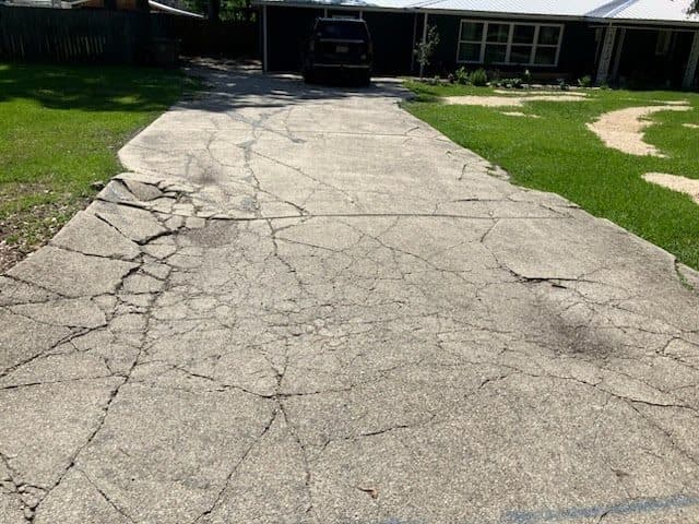 Before a cracked driveway replacement project with damaged pavement.